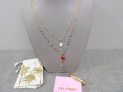 Des colliers et des bracelets sont présentés sur un mannequin tenant un sac rose