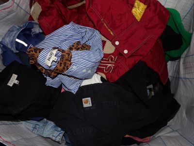 a pile of clothes that is sitting on a bed