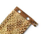 a close up of a gold bracelet on a white surface