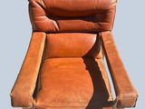 a brown leather recliner chair sitting on a blue surface