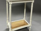 a white table with a wicker shelf on top of it