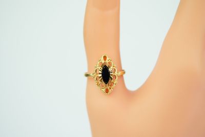an image of a woman ' s hand with a gold ring with a black stone