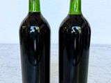 two bottles of red wine sitting on a marble counter top