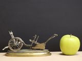 an apple sitting next to a statue of a bike and a wheelbarrower