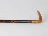 a close up of a pipe with a wooden handle on a white surface