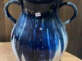 un vase bleu posé sur une table, avec une étiquette dessus
