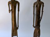 deux statues en bois représentant un homme et une femme debout l'un à côté de l'autre