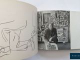 an open book with a drawing of a man sitting in a chair