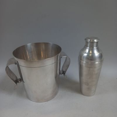 une tasse en argent et un shaker en argent posés sur une table