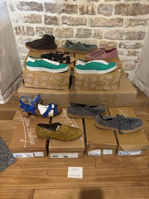 plusieurs paires de chaussures posées sur des cartons, sur un plancher en bois