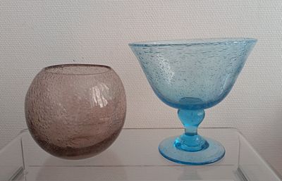 two vases sitting on a glass shelf next to each other