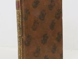 an old book with a brown cover sitting on top of a white table