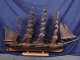 une maquette en bois d'un navire exposée sur un fond bleu