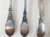 three spoons and a fork are lined up on a white surface