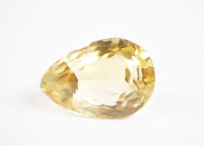 une image représentant une pierre précieuse de topaze jaune posée sur une surface blanche
