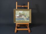a small easel with a painting on it next to a vase