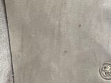 the back of a gray leather jacket with a button on it