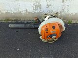 a chainsaw sitting on the ground next to a concrete wall