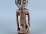 une statue en bois représentant un homme dont le visage et les mains sont posés sur sa poitrine