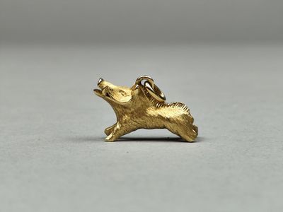 un gros plan d'une petite breloque en forme de chien en or posée sur une surface blanche