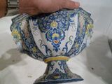 une personne tenant un vase bleu et blanc posé sur une table