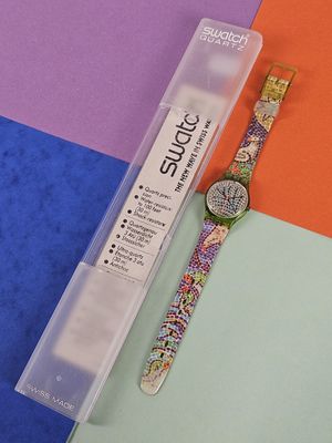 a watch sitting on a colorful surface next to a pen