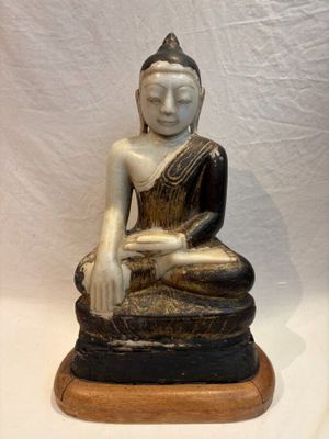 statue d'un Bouddha assis sur un socle en bois, sur fond blanc