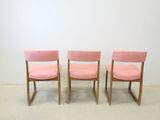 two pink chairs sitting next to each other in a room