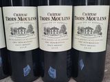 four bottles of red wine on a table with a price tag