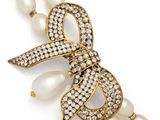 a close up of a necklace with pearls and a bow