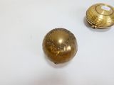 deux petits objets en laiton posés sur une surface blanche