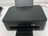 a black printer sitting on top of a white table next to a phone