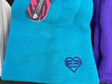 three beanies sitting on a couch with a tag on one of them