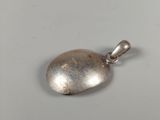 a close up of a silver pendant on a white surface