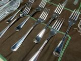many forks and spoons laid out on a table