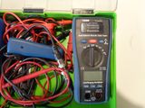 a green box with a multimeter and wires in it