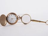 a gold pocket watch with a magnifying glass on it