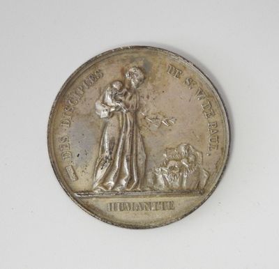 une vieille médaille en argent sur laquelle figurent une femme et un chien