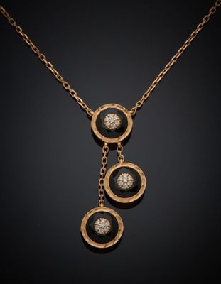 un collier en or auquel sont suspendues trois pierres noires et blanches