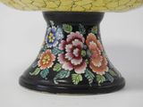 a yellow and black vase with flowers painted on it