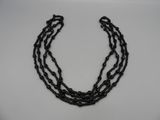 un gros plan d'un collier noir posé sur une surface blanche