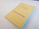 un livre jaune posé sur une table à côté d'une table blanche