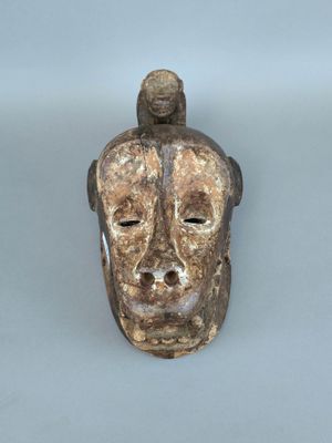 une image représentant un masque en bois surmonté d'un oiseau