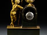a clock with a statue on top of it on a table