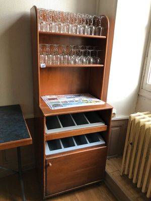 une armoire en bois sur laquelle sont posés des verres à vin et une table au plateau noir