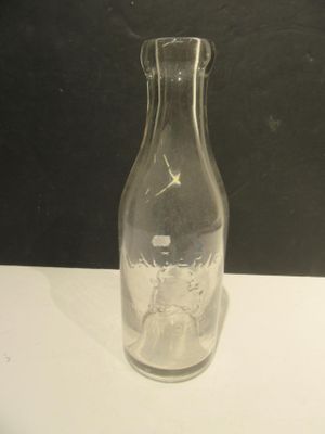 a clear glass bottle with a black lid on a white table