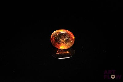 a close up of an orange diamond on a black surface