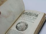 someone is holding an old book open on a white table