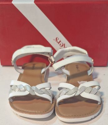 une paire de sandales blanches ornées de nœuds, posée devant une boîte rouge