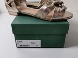 Les chaussures dorées se trouvent sur la boîte verte posée sur la table blanche.